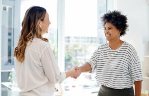 Two people shaking hands and smiling after a job interview.