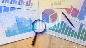 A graphic with several data paper charts with a pen and looking glass.