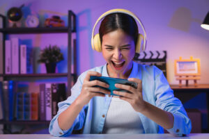 A female with headphones on; she is on her phone gaming.